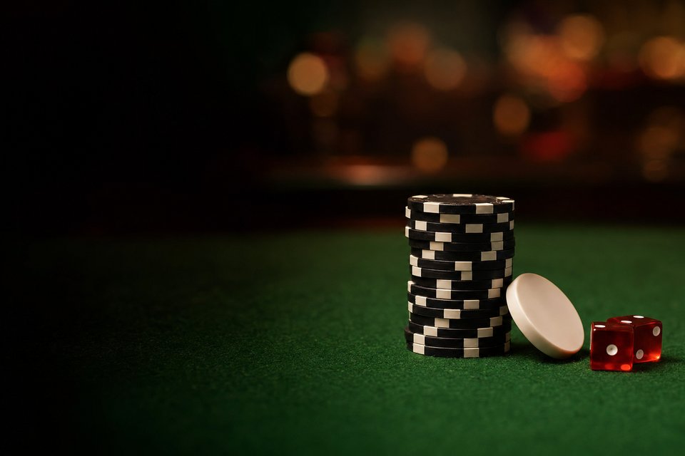 A stack of black chips beside a white puck and two red dice on green felt (AI-generated image)