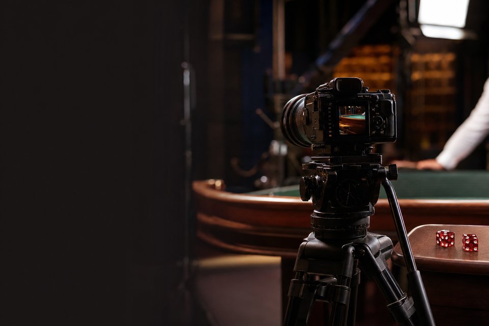 A camera on a tripod in a live dealer studio, with a craps table rail in the background (AI-generated image)