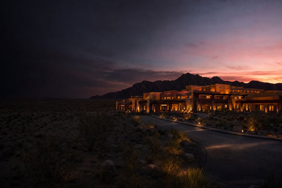 A low desert casino resort lit at night beneath a dark mountain ridge, with mesa country fading into the distance (AI-generated image)