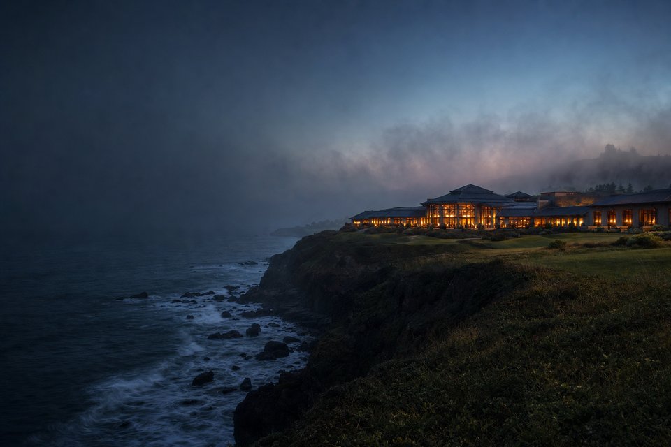 A coastal casino resort on a bluff above the Pacific at dusk, with fog rolling in over dark rocks (AI-generated image)