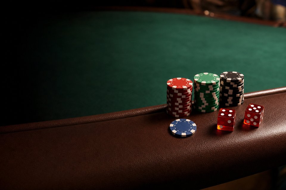 Three short stacks of chips in a row on a craps table rail, with two red dice beside them (AI-generated image)